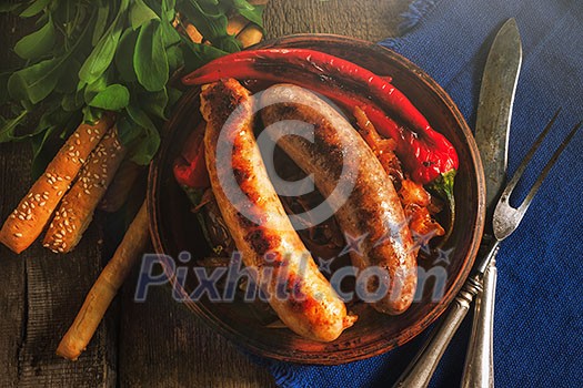 Grilled sausages and stewed cabbage on a wooden table. Rustic style. Snacks for the Oktoberfest. Top view. Grilled sausages and stewed cabbage on a wooden table. Rustic style. Snacks for the Oktoberfest. Top view.