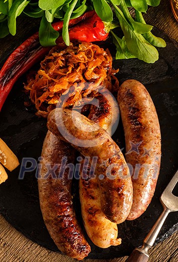 Grilled sausages and stewed cabbage with a mug of beer on a wooden table. Rustic style. Snacks for the Oktoberfest. Top view. Grilled sausages and stewed cabbage with a mug of beer on a wooden table. Rustic style. Snacks for the Oktoberfest. Top view.