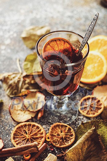 Hot mulled wine with orange, cinnamon, cardamom and anise on darken background. Autumn concept.