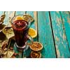 Hot mulled wine with orange, cinnamon, cardamom and anise on green wooden background.