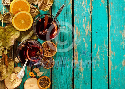 Hot mulled wine with orange, cinnamon, cardamom and anise on green wooden background. Top view.