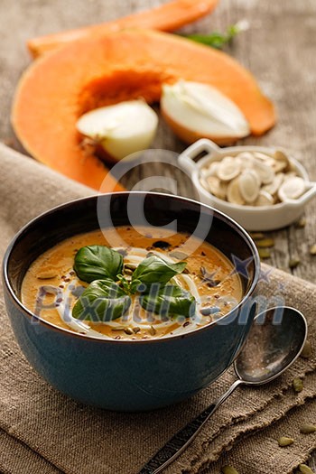 Delicious homemade pumpkin soup with basil leaves on rustic wooden table Delicious homemade pumpkin soup with basil leaves on rustic wooden table