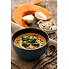 Delicious homemade pumpkin soup with basil leaves on rustic wooden table