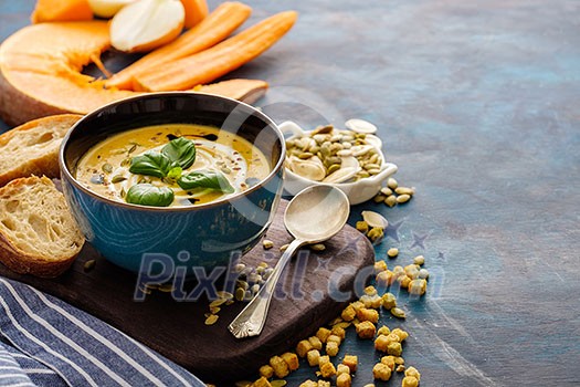 Delicious homemade pumpkin soup with basil leaves. Copyspace.