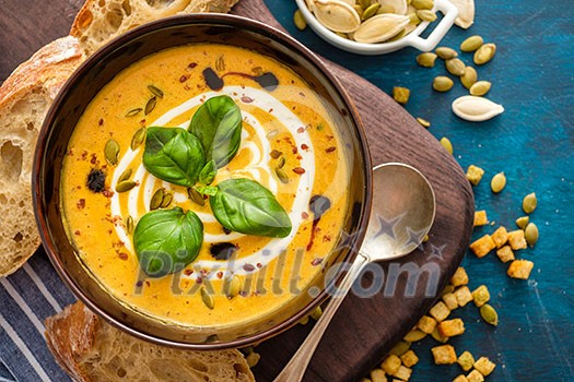 Delicious homemade pumpkin soup with basil leaves. Top view Delicious homemade pumpkin soup with basil leaves. Top view