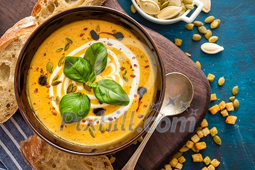 Delicious homemade pumpkin soup with basil leaves. Top view