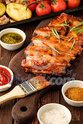 Delicious barbecued ribs seasoned with a spicy basting sauce and served with chopped fresh vegetables on an old rustic wooden chopping board. Delicious barbecued ribs seasoned with a spicy basting sauce and served with chopped fresh vegetables on an old rustic wooden chopping board.