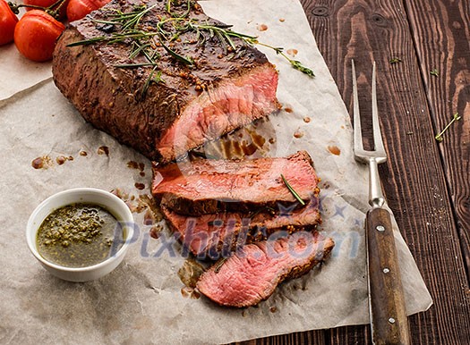 Sliced Roast beef on white paper on wooden table with grilled vegetables Sliced Roast beef on white paper on wooden table with grilled vegetables