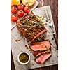 Sliced Roast beef on white paper on wooden table with grilled vegetables 