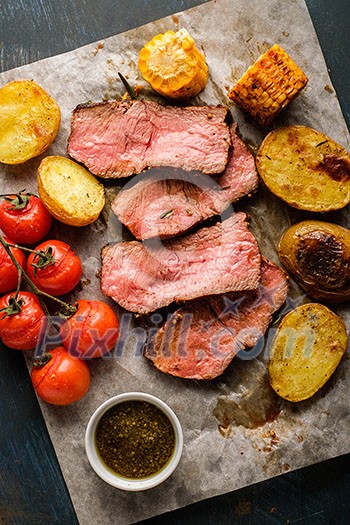 Sliced Roast beef on cutting board with grilled vegetables. View from above. Sliced Roast beef on cutting board with grilled vegetables. View from above.