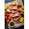 Sliced Roast beef on cutting board with grilled vegetables. View from above.