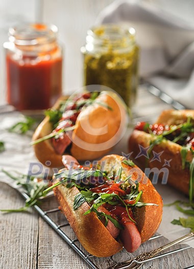 Delicious fresh hot dogs in homemade buns with arugula and ketchup on a wooden background Delicious fresh hot dogs in homemade buns with arugula and ketchup on a wooden background