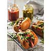 Delicious fresh hot dogs in homemade buns with arugula and ketchup on a wooden background