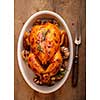 Roasted chicken  with garlic in a white plate on a wooden table. View from above.