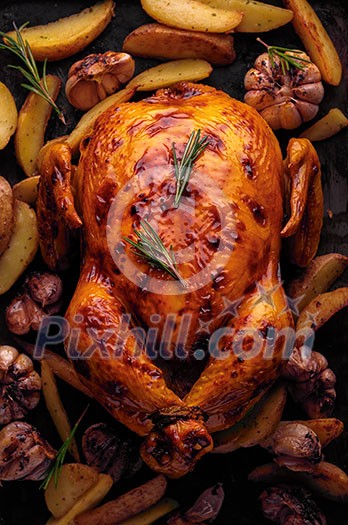 Roasted chicken with potatoes and garlic, top view.