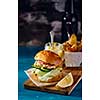 Fishburger with toppings and fries. Rustic style.