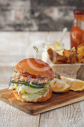 Fishburger with toppings and fries. Rustic style. Fishburger with toppings and fries. Rustic style.