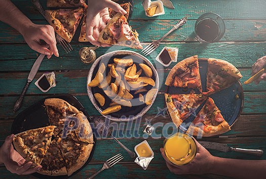 Three young girls eat pizza and drink carbonated drinks. View from above. Friendly Party. Three young girls eat pizza and drink carbonated drinks. View from above. Friendly Party.