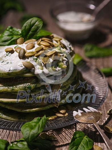 Pancakes with spinach and pumpkin seeds on a wooden table. Country style.