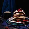 Pancakes with berries and jam on a dark background.