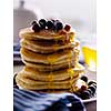 Pancakes with berries and honey on a light background.