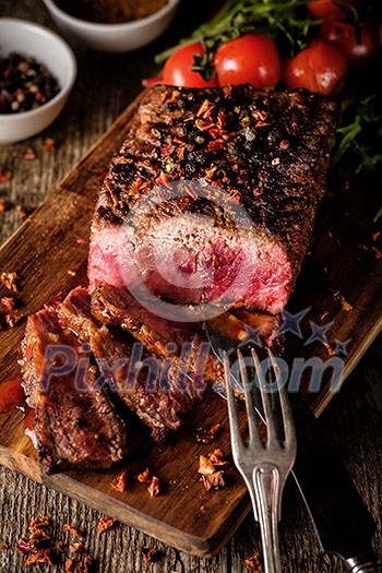 Sliced Roast beef on cutting board with grilled vegetables Sliced Roast beef on cutting board with grilled vegetables