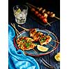 Chicken kebab on skewers with cherry, mushrooms and barbecue sauce on a blue background. 