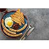 Traditional full English breakfast with fried eggs, sausages and beans on grey background. Top view.