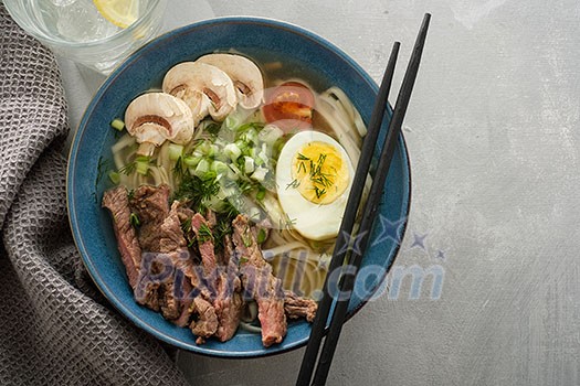 Asian ramen soup with beef, egg, chives, mushrooms in bowl. Copyspace.