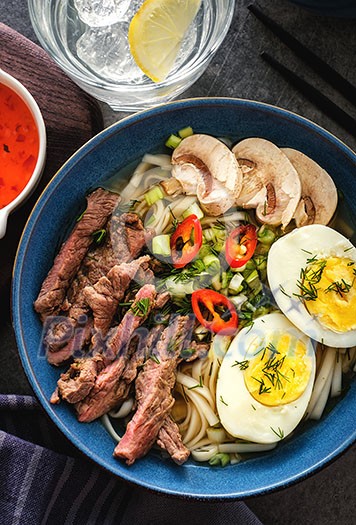 Asian ramen soup with beef, egg, chives, mushrooms in bowl. Top view.