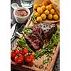 Juicy tasty grilled fillet steak served with tomatoes and cheese balls  on an old wooden board