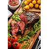 Juicy tasty grilled fillet steak served with tomatoes and cheese balls  on an old wooden board