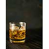 Glass of whiskey with ice on a wooden table. Shallow depth of field