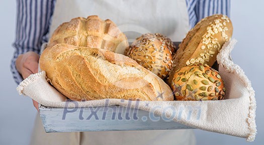 Bread assortment in the hands of the baker, horizontal banner, close-up.