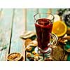 Hot mulled wine with orange, cinnamon, cardamom and anise on green wooden background.