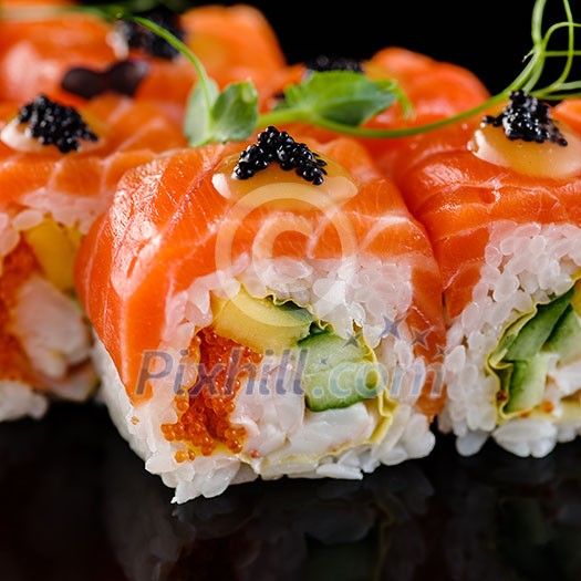 Close-up of traditional japanese sushi on a dark background with reflection. Salmon with shrimp and red caviar