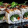 Close-up of traditional japanese sushi on a dark background with reflection. Fish Eel with Philadelphia cheese and red caviar