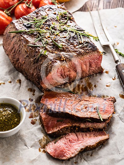 Sliced Roast beef on white paper on wooden table with grilled vegetables Sliced Roast beef on white paper on wooden table with grilled vegetables