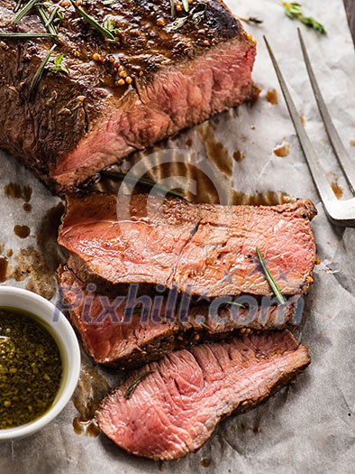Sliced Roast beef on white paper on wooden table with grilled vegetables Sliced Roast beef on white paper on wooden table with grilled vegetables