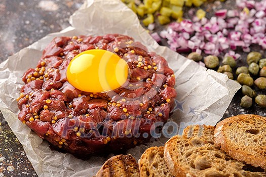 Fresh Beef Tartar is served with yolk, fried bread, pickled cucumbers and capers. Fresh Beef Tartar is served with yolk, fried bread, pickled cucumbers and capers.
