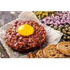 Fresh Beef Tartar is served with yolk, fried bread, pickled cucumbers and capers.