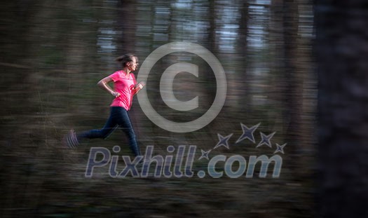 Young woman running outdoors in a forest, going fast (motion blurred image)