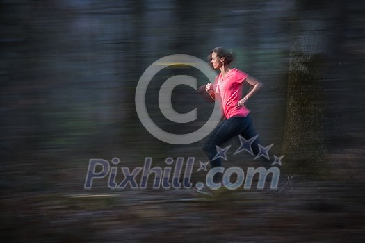 Young woman running outdoors in a forest, going fast (motion blurred image)