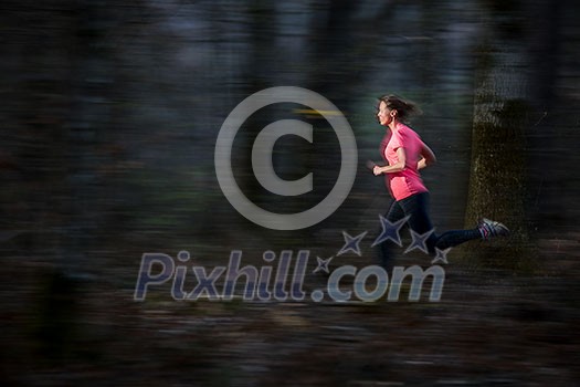 Young woman running outdoors in a forest, going fast (motion blurred image)