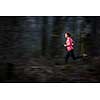 Young woman running outdoors in a forest, going fast (motion blurred image)