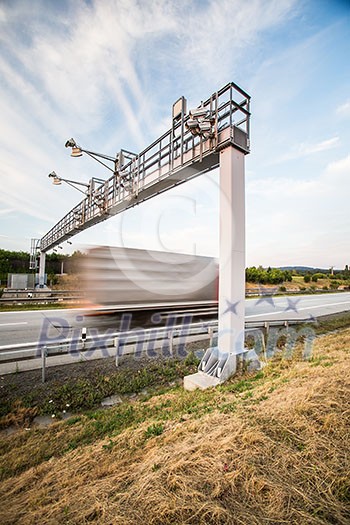 truck passing through a toll gate on a highway (motion blurred image; color toned image)