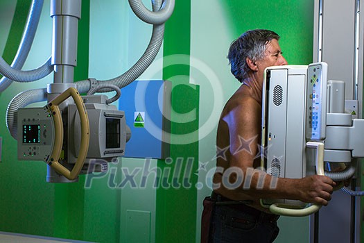 Healthcare Concept - Senior male patient undergoing an X-ray examination in a modern hospital