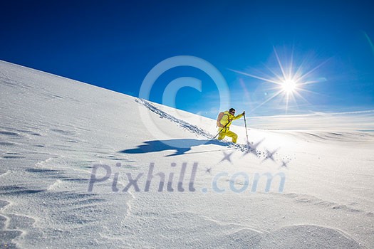 High altitude mountain explorer walking through deep snow in high mountains on a freezing winter day
