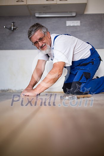 DIY, repair, building and home concept - close up of male hands lying parquet floor board/laminate flooring (shallow DOF; color toned image)