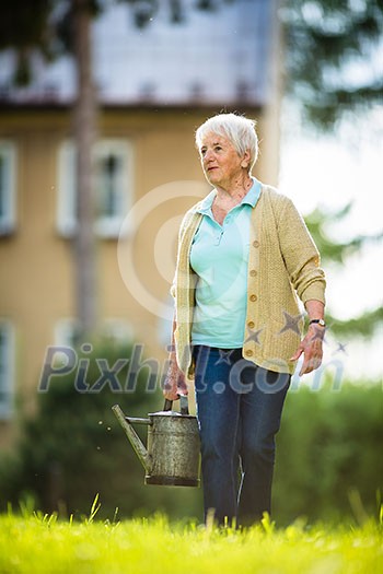 Senior woman doing some gardening in her lovely garden - watering the plants